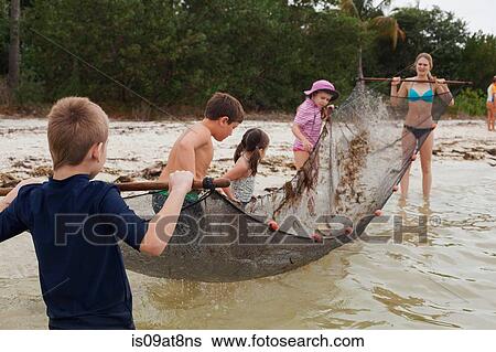 Stock Photograph - Teacher showing children how to use traditional fish net in an estuary, Sanibel Island, Pine Island Sound, Florida, USA. Fotosearch