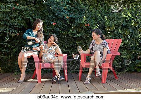 Three women drinking white wine on patio View Large Photo Image Picture - Three women drinking white wine on patio. Fotosearch