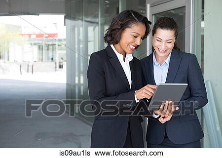 Two businesswomen, looking at digital tablet, outdoors View Large Photo Image Stock Photograph - Two businesswomen, looking at digital tablet, outdoors. Fotosearch