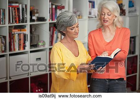 Two mature women looking at book, indoors View Large Photo Image Stock Image - Two mature women looking at book, indoors. Fotosearch
