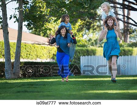 Two mothers with children on shoulders, racing, outdoors View Large Photo Image Stock Photo - Two mothers with children on shoulders, racing, outdoors. Fotosearch