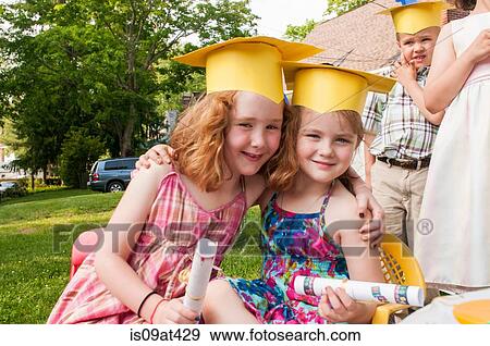 Two young girls at kindergarten graduation, wearing paper mortar boards View Large Photo Image Stock Photo - Two young girls at kindergarten graduation, wearing paper mortar boards. Fotosearch