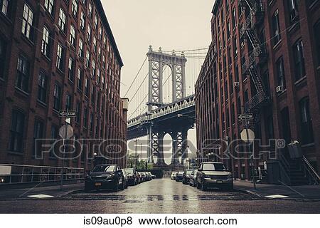 Stock Photo - View of Brooklyn Bridge between industrial buildings, New York, USA. Fotosearch
