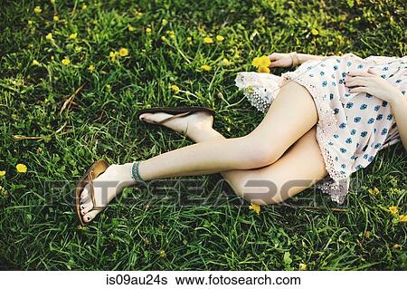 Waist down high angle view of young woman lying on grass wearing dress, flipflops and ankle bracelet View Large Photo Image Stock Photograph - Waist down high angle view of young woman lying on grass wearing dress, flipflops and ankle bracelet. Fotosearch
