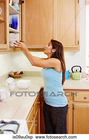 Woman putting plates into kitchen cabinet View Large Photo Image Stock Photography - Woman putting plates into kitchen cabinet. Fotosearch