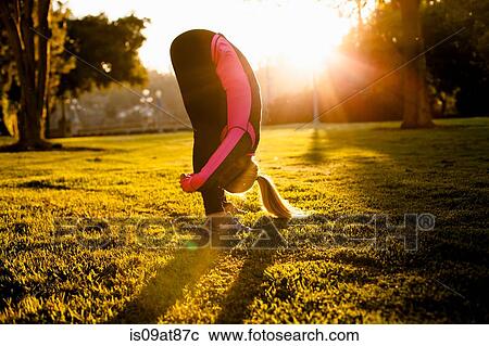 Stock Image - Woman stretching in park. Fotosearch