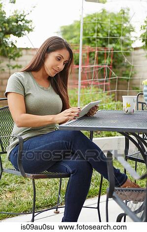 Woman using digital tablet in garden View Large Photo Image Stock Photograph - Woman using digital tablet in garden. Fotosearch