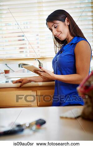 Woman using digital tablet in kitchen View Large Photo Image Stock Photography - Woman using digital tablet in kitchen. Fotosearch