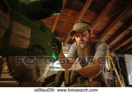 Stock Image - Wood artist using machinery in workshop. Fotosearch