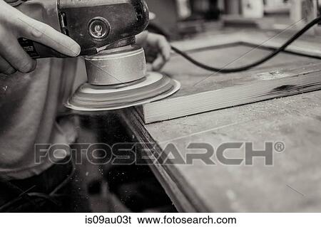 Stock Photograph - Wood artist working in workshop, using machinery, close-up. Fotosearch