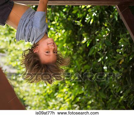 Stock Image - Young boy hanging upside-down. Fotosearch