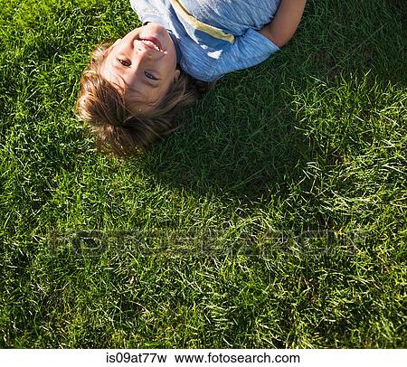 Young boy lying on grass, overhead view View Large Photo Image Stock Photo - Young boy lying on grass, overhead view. Fotosearch