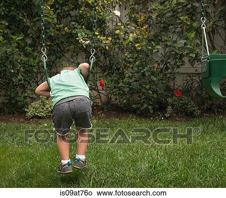 Young boy playing on garden swing, rear view View Large Photo Image Picture - Young boy playing on garden swing, rear view. Fotosearch