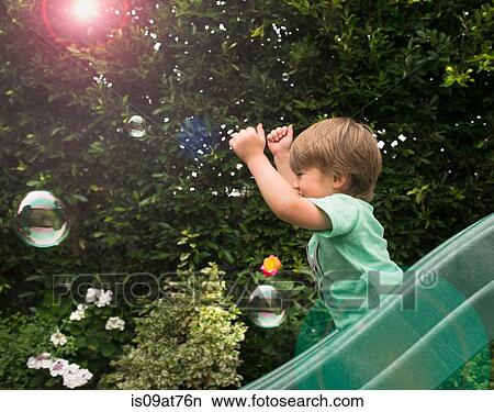 Young boy sliding down garden slide View Large Photo Image Picture - Young boy sliding down garden slide. Fotosearch