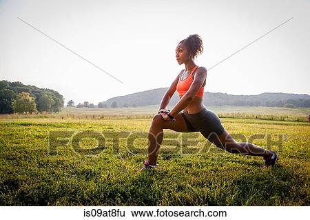 Young female runner stretching in rural park View Large Photo Image Stock Photograph - Young female runner stretching in rural park. Fotosearch