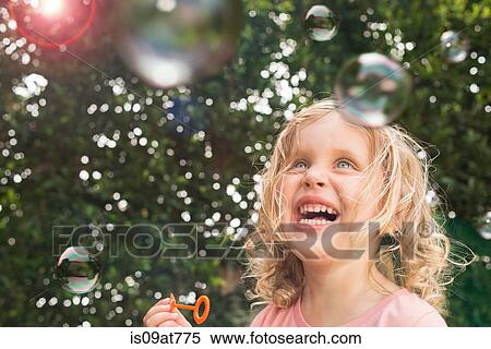 Young girl blowing bubbles, outdoors View Large Photo Image Stock Photography - Young girl blowing bubbles, outdoors. Fotosearch
