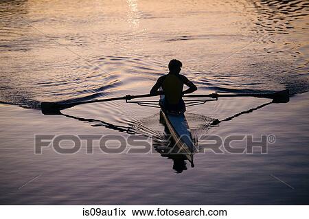 Stock Photo - Young man rowing on river at sunset. Fotosearch