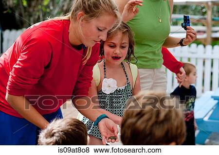 Young woman holding sea creature, showing children View Large Photo Image Stock Photo - Young woman holding sea creature, showing children. Fotosearch