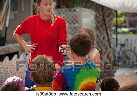 Young woman holding starfish, children looking View Large Photo Image Stock Image - Young woman holding starfish, children looking. Fotosearch