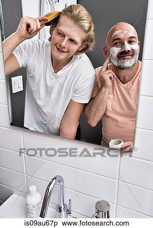 Bathroom mirror image of male couple shaving and brushing hair View Large Photo Image Stock Photography - Bathroom mirror image of male couple shaving and brushing hair. Fotosearch