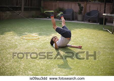 Boy in garden lying on grass, legs raised View Large Photo Image Stock Image - Boy in garden lying on grass, legs raised. Fotosearch