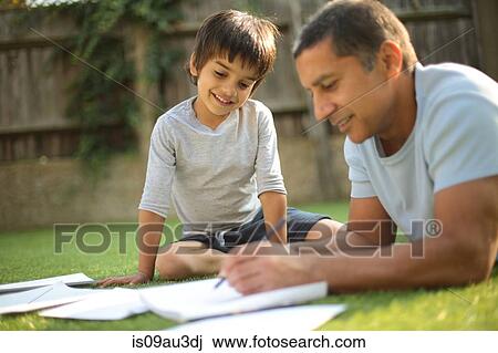 Boy sitting on grass watching father do paperwork looking down smiling View Large Photo Image Stock Image - Boy sitting on grass watching father do paperwork looking down smiling. Fotosearch