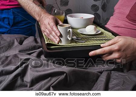 Close up of man placing coffee cup on breakfast tray to boyfriend in bed View Large Photo Image Stock Photo - Close up of man placing coffee cup on breakfast tray to boyfriend in bed. Fotosearch