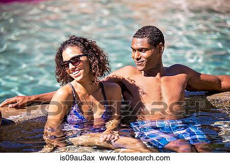 Couple sitting in swimming pool looking away smiling View Large Photo Image Stock Photo - Couple sitting in swimming pool looking away smiling. Fotosearch