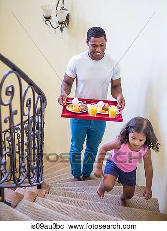 Father and daughter walking up stairs carrying breakfast on tray View Large Photo Image Stock Image - Father and daughter walking up stairs carrying breakfast on tray. Fotosearch
