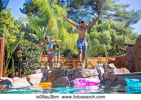 Full length front view of father and daughter mid air jumping into swimming pool View Large Photo Image Picture - Full length front view of father and daughter mid air jumping into swimming pool. Fotosearch