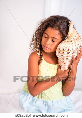 Girl holding seashell to ear, eyes closed listening View Large Photo Image Stock Image - Girl holding seashell to ear, eyes closed listening. Fotosearch