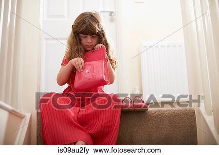 Girl wearing red on stairway looking in handbag View Large Photo Image Stock Photo - Girl wearing red on stairway looking in handbag. Fotosearch
