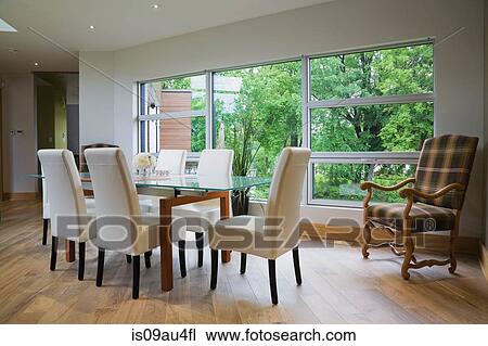 Glass dining table and leather chairs in front of large window in modern dining room View Large Photo Image Stock Image - Glass dining table and leather chairs in front of large window in modern dining room. Fotosearch