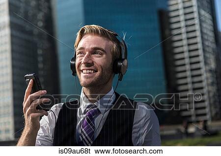 Happy young businessman in front of office wearing headphones, New York, USA View Large Photo Image Stock Photograph - Happy young businessman in front of office wearing headphones, New York, USA. Fotosearch