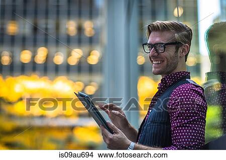 Happy young businessman leaning against park window using digital tablet View Large Photo Image Picture - Happy young businessman leaning against park window using digital tablet. Fotosearch