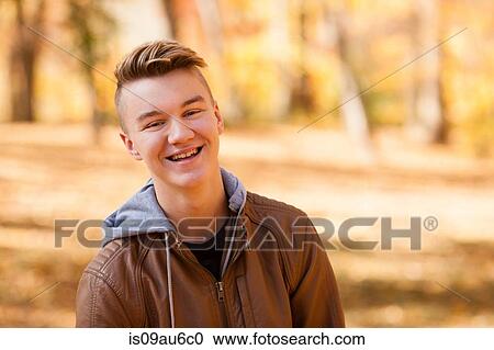 Stock Image - Head and shoulder portrait of teenage boy wearing leather jacket in autumn forest. Fotosearch