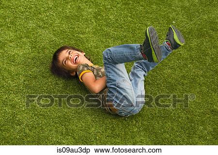 High angle view of boy lying on grass legs raised looking away laughing View Large Photo Image Stock Photography - High angle view of boy lying on grass legs raised looking away laughing. Fotosearch