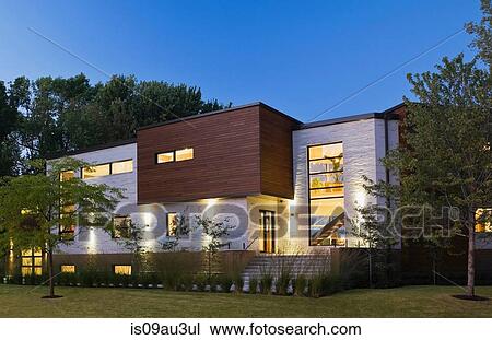 Illuminated beige stone with brown cedar wood modern cubist style residential home facade at dusk, Quebec, Canada View Large Photo Image Stock Image - Illuminated beige stone with brown cedar wood modern cubist style residential home facade at dusk, Quebec, Canada. Fotosearch