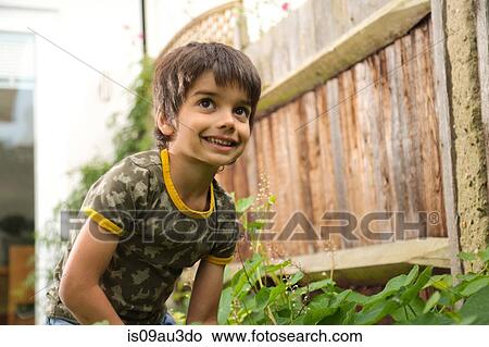 Low angle portrait of boy in garden looking away smiling View Large Photo Image Picture - Low angle portrait of boy in garden looking away smiling. Fotosearch