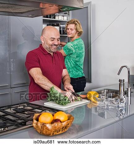 Stock Image - Male couple preparing food in kitchen. Fotosearch