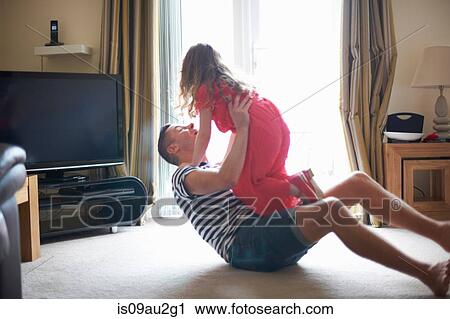 Mature man lying on living room floor playing with daughter View Large Photo Image Stock Image - Mature man lying on living room floor playing with daughter. Fotosearch