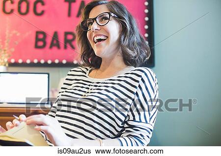 Mid adult woman at desk, laughing, looking away View Large Photo Image Stock Photograph - Mid adult woman at desk, laughing, looking away. Fotosearch