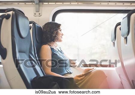 Mid adult woman on train, holding digital tablet, looking out of window View Large Photo Image Stock Image - Mid adult woman on train, holding digital tablet, looking out of window. Fotosearch