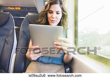 Mid adult woman on train using digital tablet View Large Photo Image Stock Photograph - Mid adult woman on train using digital tablet. Fotosearch