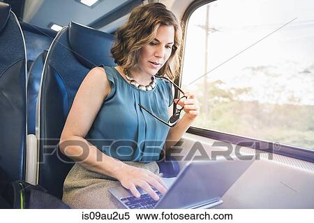 Mid adult woman on train, using laptop View Large Photo Image Stock Photography - Mid adult woman on train, using laptop. Fotosearch