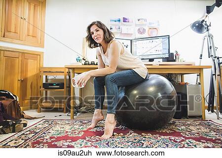 Mid adult woman sitting on yoga ball, holding coffee cup View Large Photo Image Stock Image - Mid adult woman sitting on yoga ball, holding coffee cup. Fotosearch