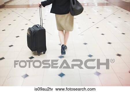Mid adult woman walking with wheeled suitcase, rear view, low section View Large Photo Image Stock Photo - Mid adult woman walking with wheeled suitcase, rear view, low section. Fotosearch