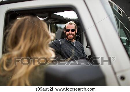 Over the shoulder view of young woman chatting to boyfriend in jeep View Large Photo Image Stock Image - Over the shoulder view of young woman chatting to boyfriend in jeep. Fotosearch