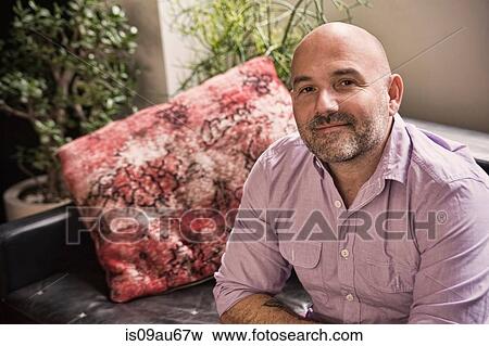 Portrait of confident mature man sitting on sofa View Large Photo Image Stock Photo - Portrait of confident mature man sitting on sofa. Fotosearch