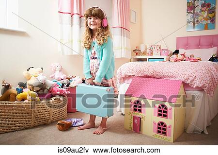 Portrait of girl in bedroom holding suitcase and wearing headphones View Large Photo Image Stock Photo - Portrait of girl in bedroom holding suitcase and wearing headphones. Fotosearch